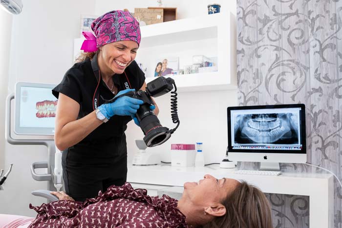 The dentist is smiling while is taking a photo of the patient before a smile makeover treatment in Cancun.